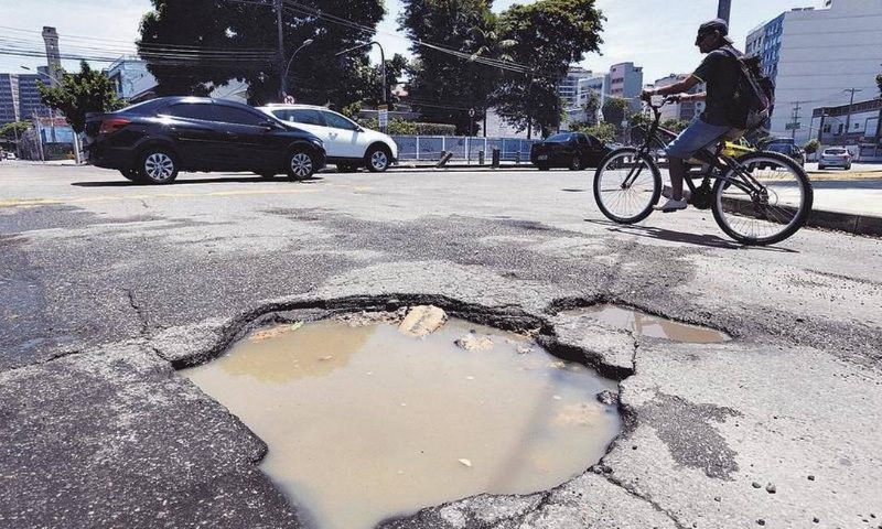 Buraco grande com água parada no meio de rua urbana brasileira